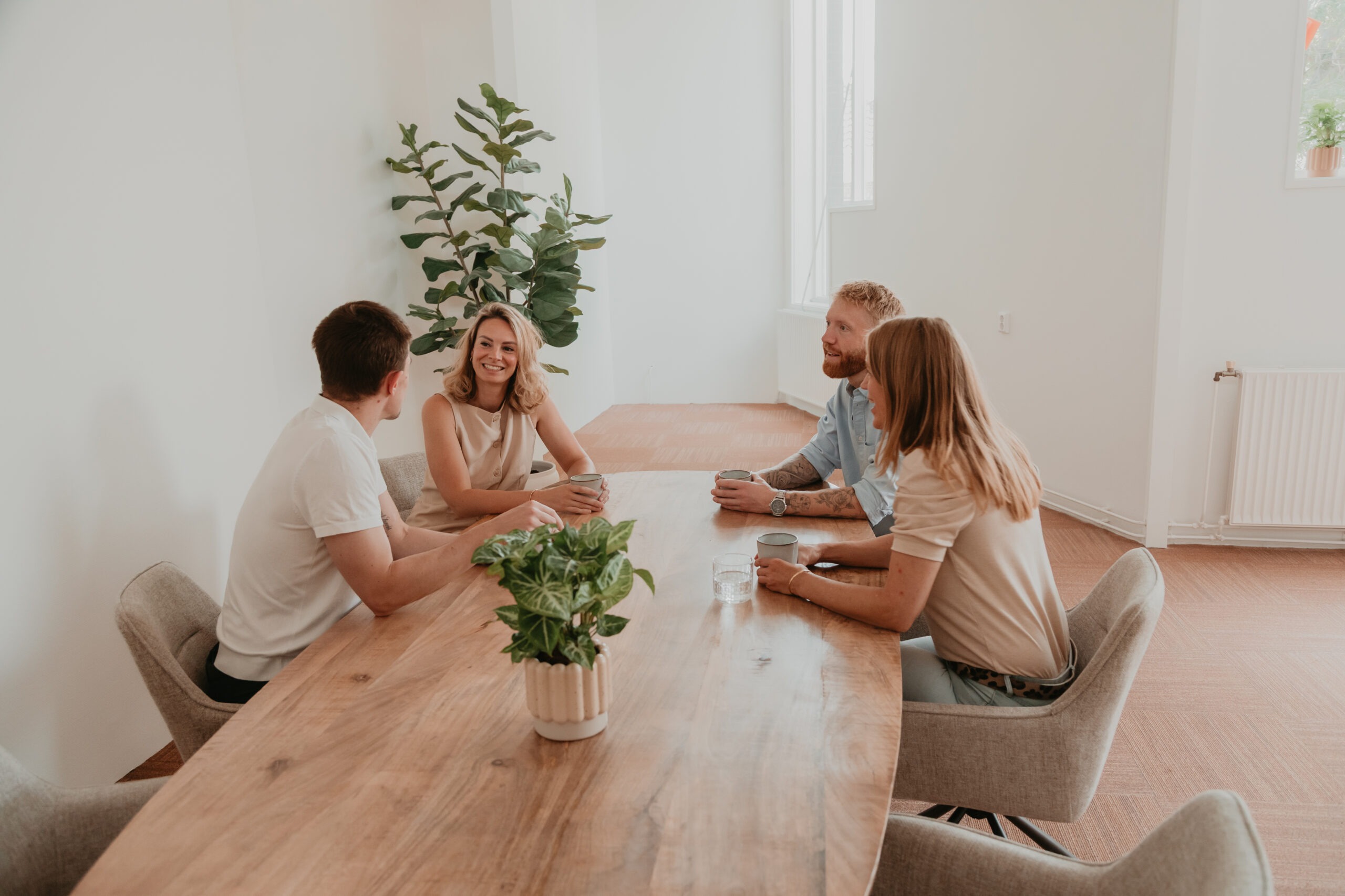 Vier collega’s van ZorgSterk in gesprek aan een tafel op kantoor